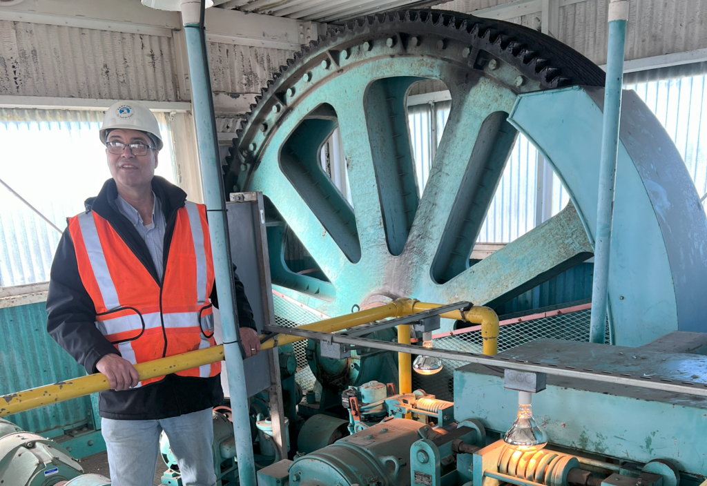 A man in a hard hat stands in front of machinery